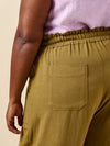 Person wearing mustard yellow pantsmade using Sepia Pants and Shorts sewing pattern with a pocket on a beige background