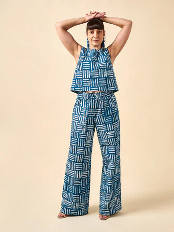 Woman wearing a blue geometric patterned outfit made using Sepia Pants and Shorts sewing patternon a beige background