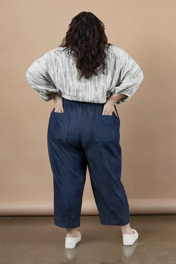 Person wearing a striped shirt and blue pants made using Sepia Pants and Shorts sewing pattern against a beige background