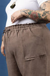 Brown pants made using Sepia Pants and Shorts sewing patternworn by a person with tattoos on a blue background