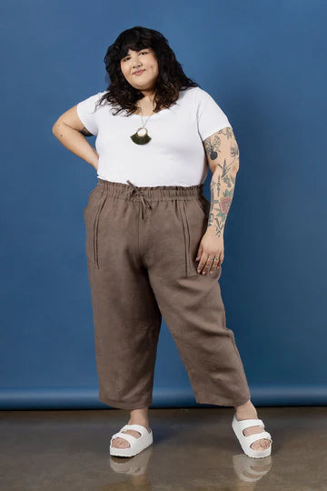 Person wearing a white t-shirt and brown pants made using Sepia Pants and Shorts sewing patternagainst a blue background