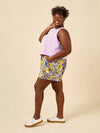 Woman wearing a colourful short made using Sepia Pants and Shorts sewing patternand light purple top on a beige background