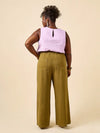 Woman wearing a light purple sleeveless top and green wide-leg pants made using Sepia Pants and Shorts sewing pattern on a beige background
