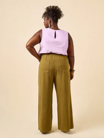Woman wearing a light purple sleeveless top and green wide-leg pants made using Sepia Pants and Shorts sewing pattern on a beige background