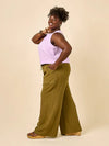 Woman wearing a light purple sleeveless top and green wide-leg pants made using Sepia Pants and Shorts sewing pattern on a beige background