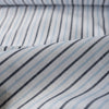 Alternating sky blue and midnight vertical stripes on a white linen blend fabric, with a natural slub texture and soft appearance.