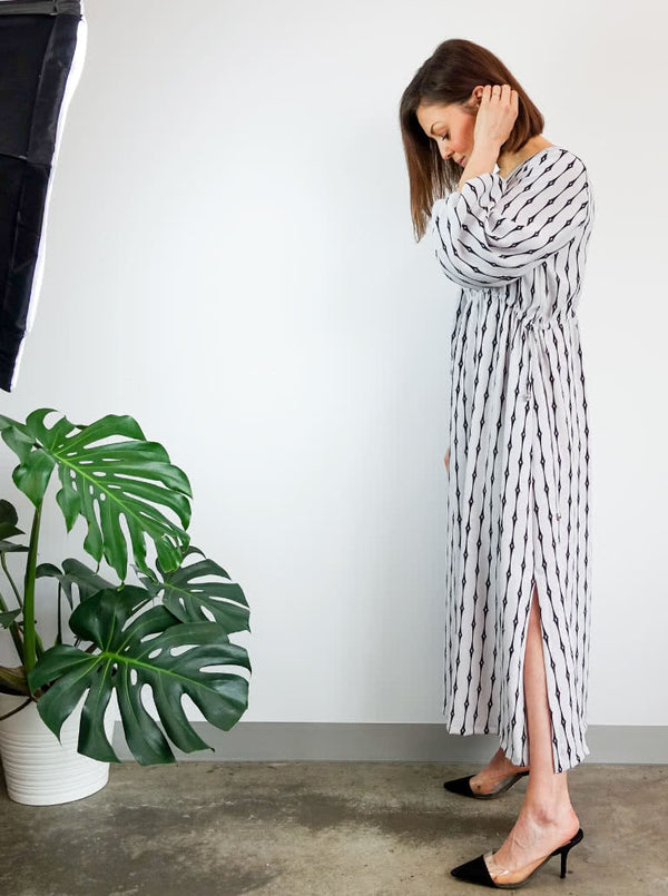 A fashionable Naomi woven dress sewing pattern with a V-neck, angled waist seam, and draw-string waist, ideal for an easy-fit, stylish garment.