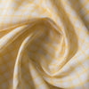 Subtle and soft Sunny Check linen fabric with lemon and white checks, offering a fine weave and gentle drape for elegant apparel.