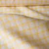 Subtle and soft Sunny Check linen fabric with lemon and white checks, offering a fine weave and gentle drape for elegant apparel.