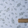 Soft green foliage patterns on white Leafy Whisper Linen Blend Fabric, 160 GSM, ideal for eco-friendly fashion and décor.