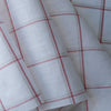 Harmony Checks Linen Blend Fabric. A lightweight linen-cotton blend fabric with a plaid pattern of thin red stripes forming a grid on a light beige background, indicating a composition of 52% linen and 48% cotton and a weight of 135 GSM.