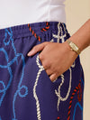 Person wearing a navy blue pants with rope pattern and white shirt, hand in pocket.