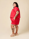 Person wearing a red outfit with tattoos on a beige background