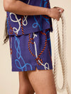 Person wearing a blue outfit with rope pattern holding a rope against a beige background