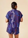 Person wearing a purple outfit with colorful patterns on a beige background