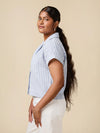 Woman wearing a blue and white striped shirt against a beige background