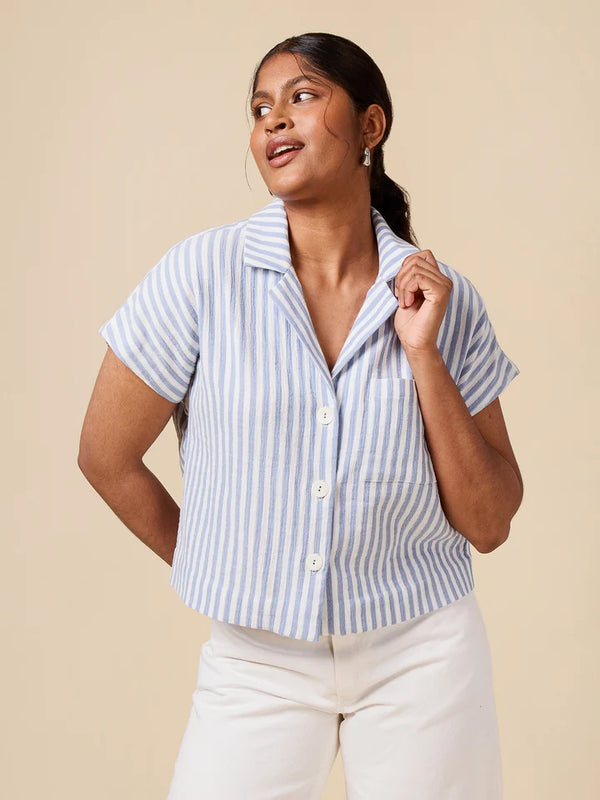 Woman wearing a blue and white striped shirt against a beige background
