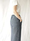 side view of lady wearing blue stripped linen pant made using Fifi Woven Pant sewing pattern, featuring a wide leg design with a smooth front yoke, elastic back, and side pockets, perfect for crepe, linen, and rayon fabrics.