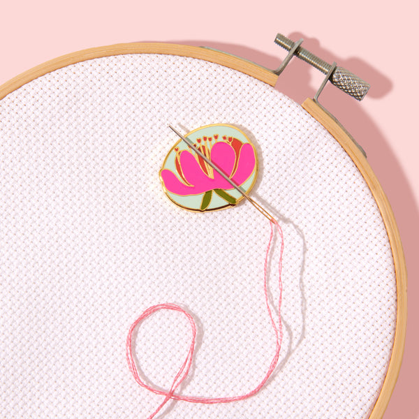 Embroidery hoop with pink thread and a floral embroidery design on a light pink background