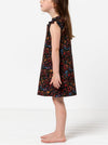 Young girl wearing a floral dress made using andie kids dress sewing patternon a white background