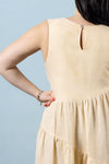 Beige dress worn made using Azure Dress, Skirt, and Top sewing pattern by a person against a light blue background