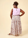 Woman wearing a sleeveless top and floral skirt on a beige background