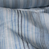 Vintage-style Blue Multi Stripe 100% Linen Fabric with varying stripes in navy, blue, and white on a light blue background, offering a washed-out look.