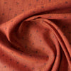 Close-up of burnt orange linen fabric with chocolate damask-style floral print and textured slubby yarn-dyed fibers