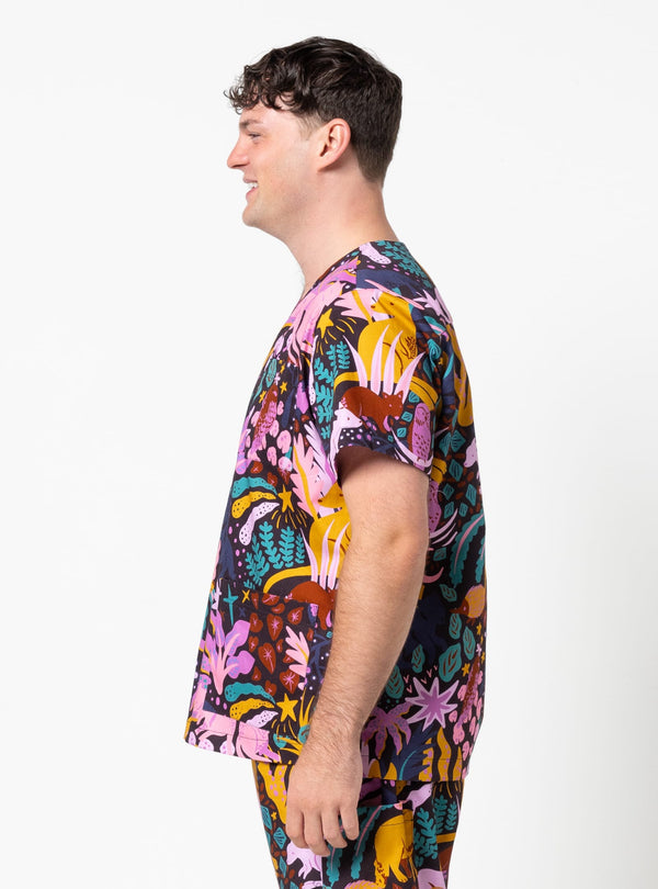 Person wearing a colorful tropical patterned shirt on a white background