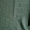 Close-up of Forest Chambray linen fabric in deep earthy green with green-and-black chambray weave, 100% linen, 160 GSM