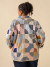 Person wearing a patchwork jacket with a beige background