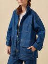 Person wearing a blue denim jacket on a beige background