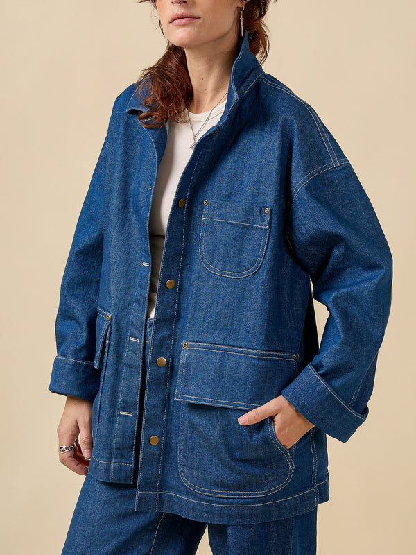 Person wearing a blue denim jacket on a beige background