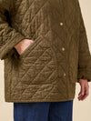 Quilted jacket with diamond pattern and gold buttons on a beige background