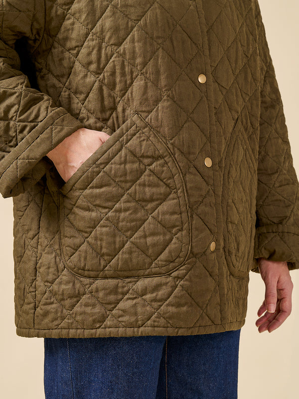 Quilted jacket with diamond pattern and gold buttons on a beige background