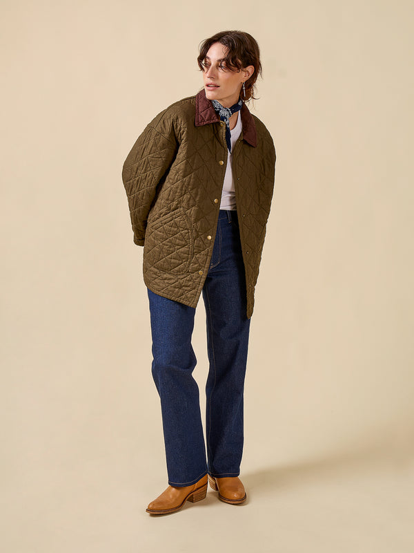 Person wearing a quilted green jacket on a beige background