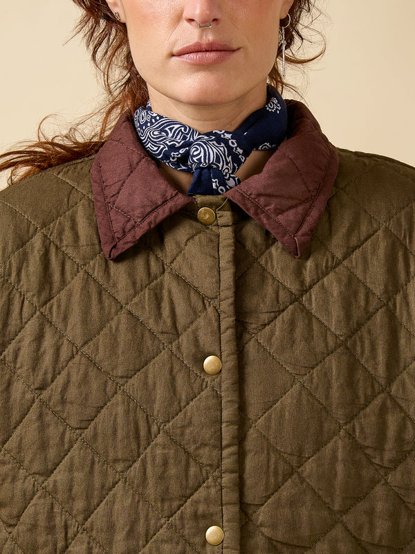 Close-up of a person wearing a quilted jacket with a patterned scarf around their neck.