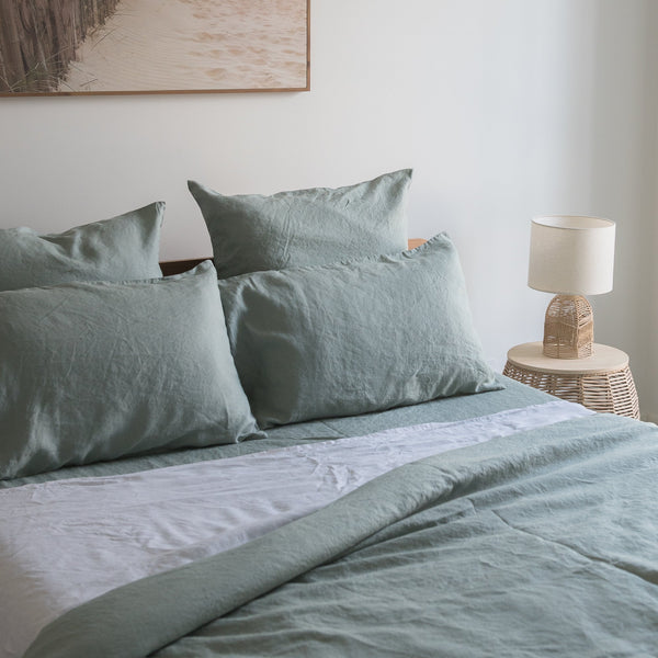 Bed with Harbour Sage linen fitted sheetand pillows in a bedroom setting.