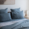 Lake Blue flat sheet 100% linen on a bed with a lamp and painting in the background