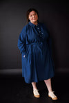 Person wearing a blue dress against a black background