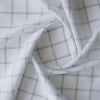 Mossy Grid linen-cotton blend fabric with a white base and moss-colored grid, lightweight and sheer with a loose weave.