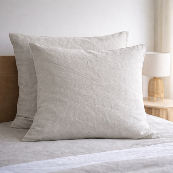 TwoNatural European linen pillowcaseson a bed with a neutral background