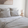 Neatly made bed withNatural linen fitted sheetand pillows in a bedroom setting.