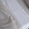Close-up of Natural linen flat sheet soft beige bedding and white fabric with a textured pattern