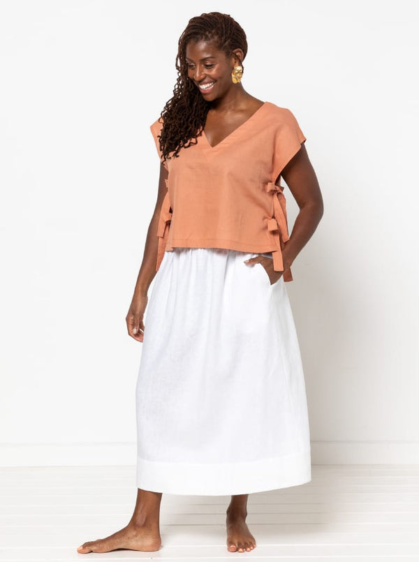 Woman wearing a peach top and white skirt made using Rumi Top Sewing Pattern on a white background