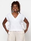 Woman wearing a white blouse with cap sleeves made using Rumi Top Sewing Pattern against a plain background