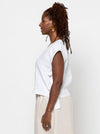 Woman wearing a white sleeveless top made using Rumi Top Sewing Pattern and beige pants against a plain background