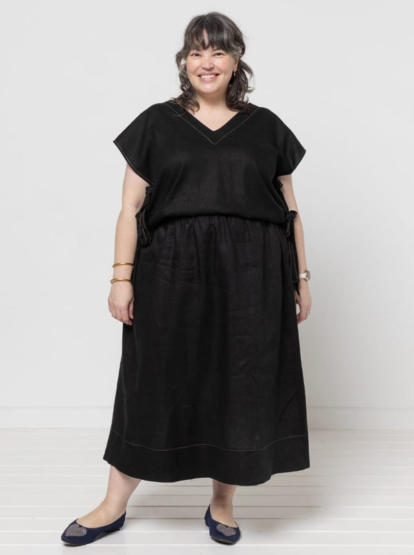 Woman wearing a black dress made using Rumi Top Sewing Pattern against a white background