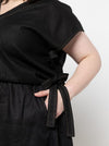 Black dress made using Rumi Top Sewing Pattern with a tie waist worn by a person on a white background