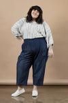 Woman wearing a white patterned top and blue pants made using Sepia Pants and Shorts sewing patternagainst a beige background
